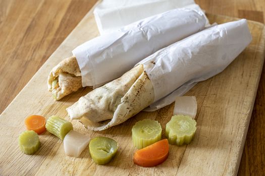 Fresh shawarma sandwiches with vegetables pickles ready to eat on a wooden cutting board