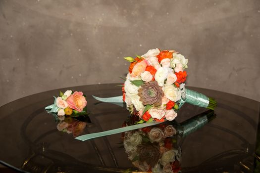 wedding bouquet and boutonniere on a transparent glass table