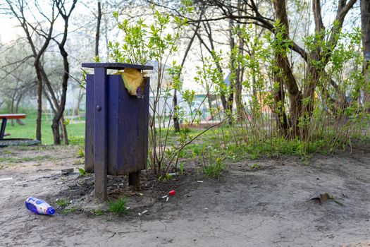 Full trash can and bottle on the ground