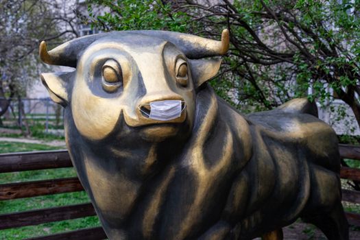 a bronze bull sculpture in a medical mask is protected against coronavirus