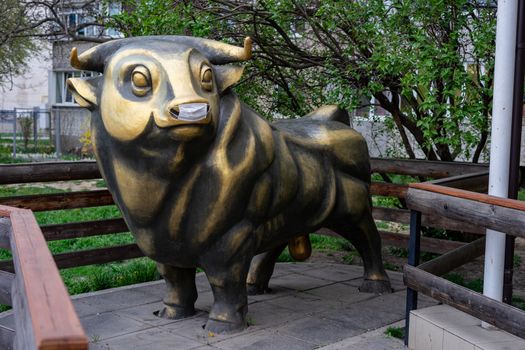 a bronze bull sculpture in a medical mask is protected against coronavirus