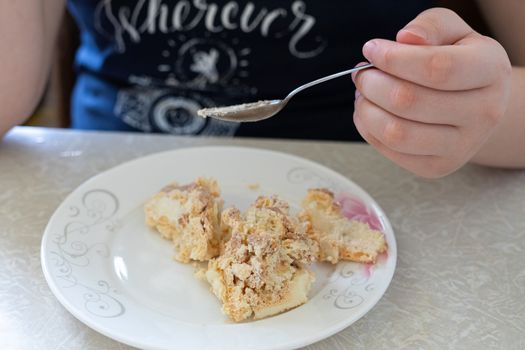 baby with a small spoon eats a delicious cake