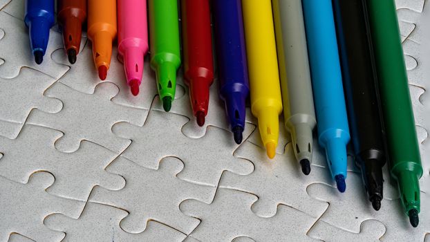 A multicolored pen on a white jigsaw background, color drawing device