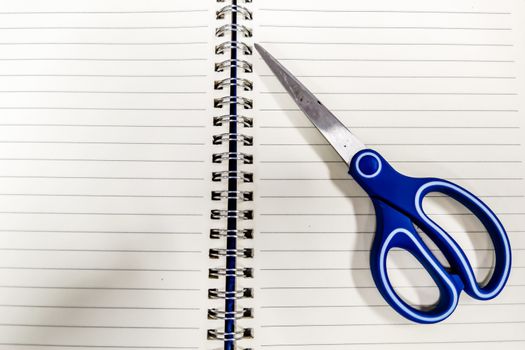 Blue handle scissors placed on a notebook