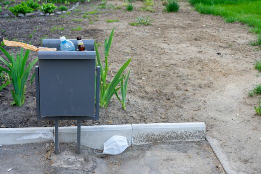 a protective medical mask is lying on the ground near the trash