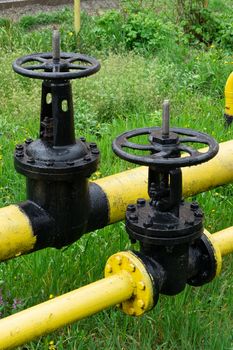 two massive black valves on a yellow gas pipe