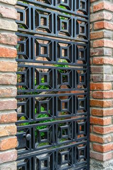 metal wrought iron door lattice in a red brick fence