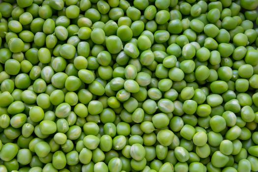 Background of young juicy green peeled peas mound