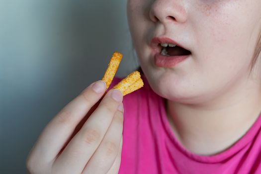 The girl puts in her mouth a few breadcrumbs. The girl eats crackers