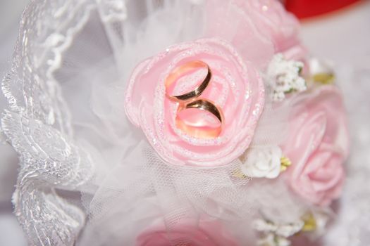 Golden wedding rings on a pink rose