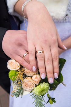 Hands of brides with wedding rings on a wedding bouquet background