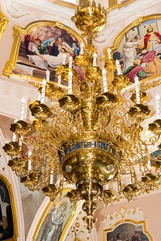 Large gilded chandelier in the temple of God on the background of icons and murals