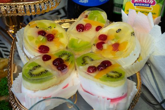 Jelly from milk, sour cream, kiwi and other fruits. Several large jellies lie on a plate