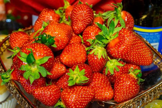 Red fresh strawberries lie on a slide on a beautiful plate