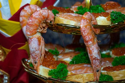 Shrimp and sandwiches with red caviar decorated with greens