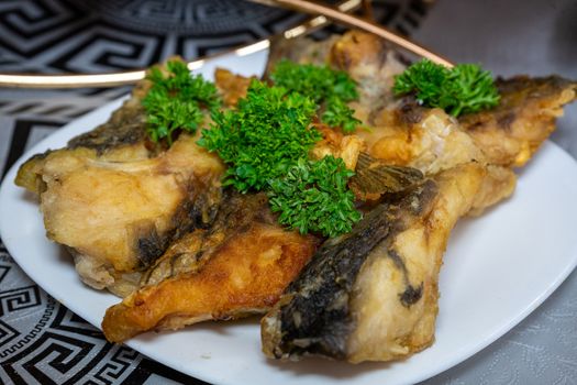 Golden fried fish decorated with parsley. Fried fish on a plate