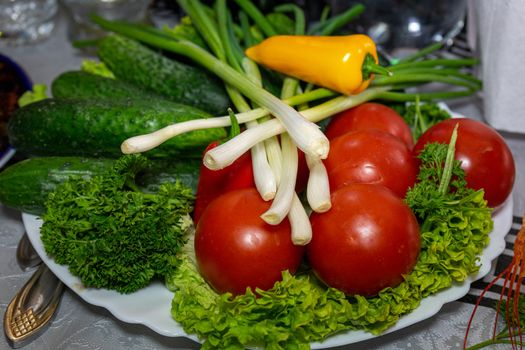 Fresh vegetables on a plate. Vegetarian food. Tomatoes, cucumbers, onions, parsley