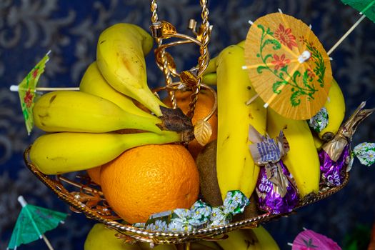 Ukraine, Vinnytsia - May 23, 2020. Fruits and candies on a plate. Bananas, oranges, kiwis and candies