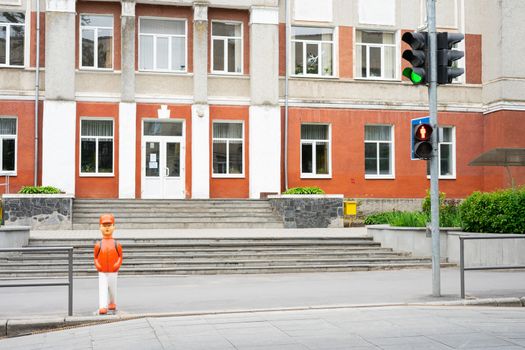 Ukraine, Vinnytsia, 2020.  Statuette of a schoolboy about to cross the road. Warning sign near the school