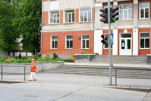 Ukraine, Vinnytsia, 2020.  Statuette of a schoolboy about to cross the road. Warning sign near the school