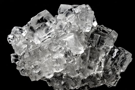 Cubic salt crystal aggregate against black background, isolated