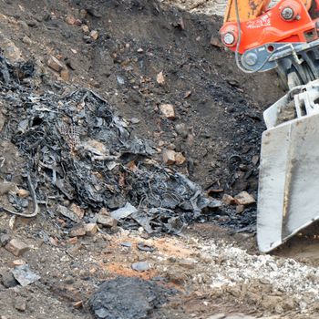 Former rubbish dump in the excavation pit, black discoloured and contaminated soil, old deposit with waste in a construction area for residential buildings