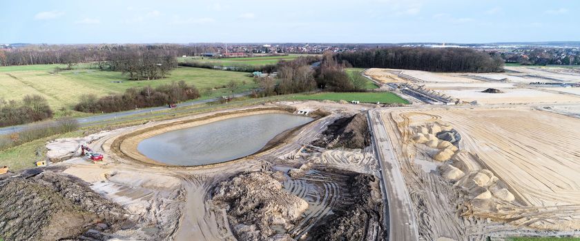Aerial view of a construction site for a new development area with a new rainwater retention basin at great height, with a drone