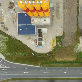 Aerial view of a construction site for a cement plant, with an asphalted road with signs in the foreground, made by drone