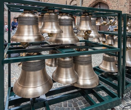 Bruges, Flanders, Belgium -  June 15, 2019: Larger selection of heavy metal and shiny Petit and Fritsen bells of carillon, set in green contraption on square inside Belfry.