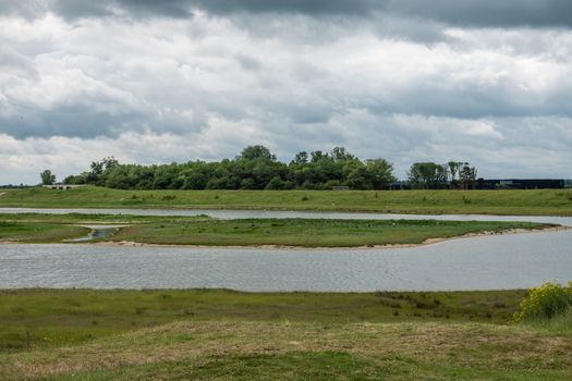 Knokke-Heist, Flanders, Belgium -  June 16, 2019: Knokke-Zoute part of town. Zwin bird refuge plain shows plenty of them set on green and in salt water creeks under cloudscape. Tree line on horizon.