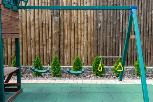 Children's swing. Playground in the yard with a fence