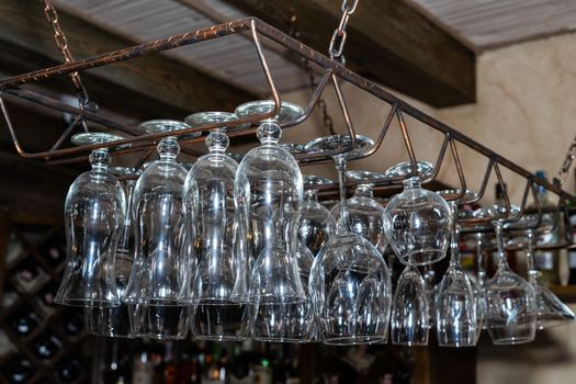 Many glass goblets hang over the bar. Empty glasses