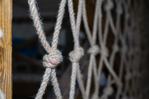 Wall made of rope mesh. Soft focus. Knot made of gray rope