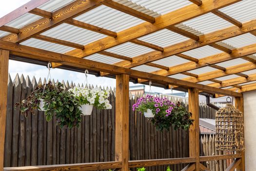 Ceiling and wall of wooden beams. Hanging pots with flowering plants