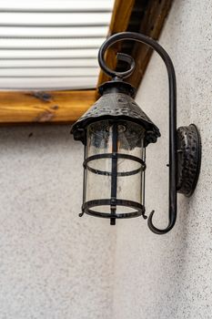 An iron black lamp is attached to the wall. Lamp on the wall close up