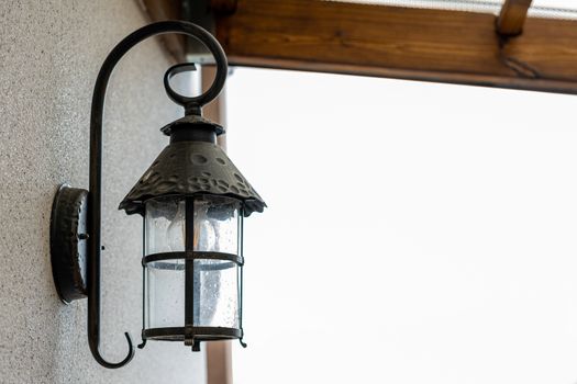 A black lamp is attached to the wall of the house from the outside. Place under the inscription.