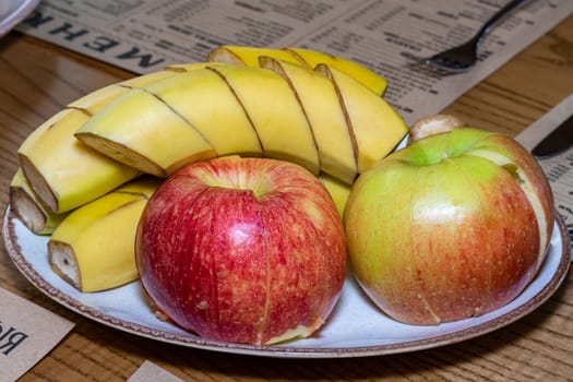 Fruit slices on a plate. Plate with fruit on the table. Apple and banana cut into slices