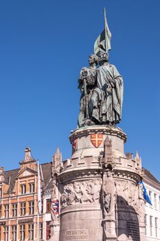 Bruges, Flanders, Belgium -  June 17, 2019: Green bronze statue of Jan Breydel and Pieter De Coninck on Mark Square against full blue sky. Gables in back.