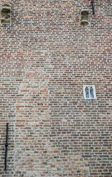 Bruges, Flanders, Belgium -  June 17, 2019: Smallest window of Europe is set in brown-gray brick wall of Gruuthuse castle.