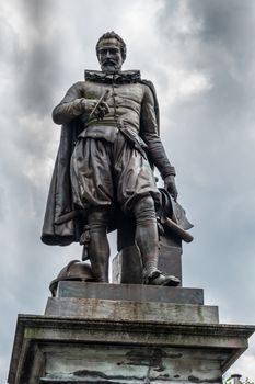 Bruges, Flanders, Belgium -  June 17, 2019: Closeup of Simon Stevin statue isolated against dark rainy cloudscape.