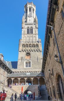 Bruges, Flanders, Belgium -  June 17, 2019: The Belfry tower, Halletoren, seen from within central court of the halls. People line up to mount the steps inside the tower.