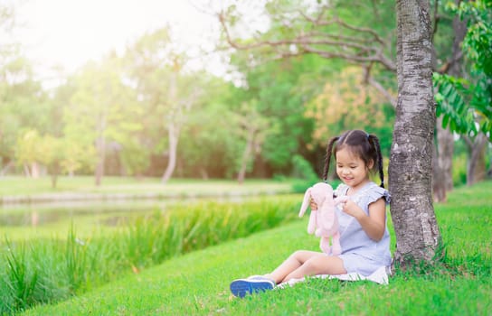 Cute little asian girl with a doll in the park