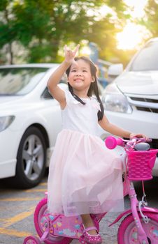 Cute little asian girl riding a bicycle with sunlight, kids sport and active lifestyle
