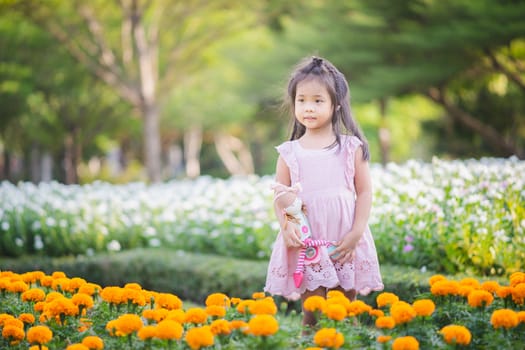 Cute little asian girl with a doll in the garden