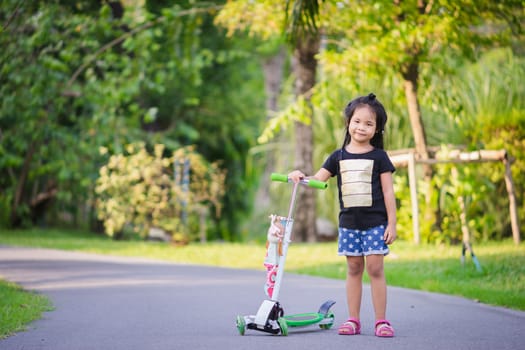 Portrait of cute little asian girl and scooter in a park