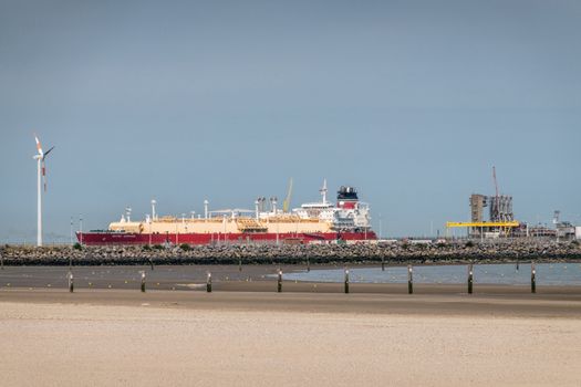 Zeebrugge, Flanders, Belgium -  June 18, 2019: British Saphire LNG tanker docked at LNG terminal in port of Zeebrugge under blue sky as seen from beach in Knokke-Heist.
