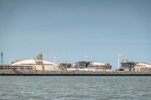 Zeebrugge, Flanders, Belgium -  June 18, 2019: Closeup of LNG terminal in port of Zeebrugge under blue sky as seen from beach in Knokke-Heist.