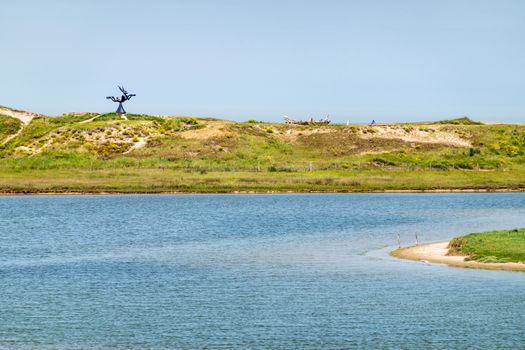 Knokke-Heist, Flanders, Belgium -  June 18, 2019: Zwin Bird Refuge. Landscape with salt water creek in front of the dunes protecting from Nord Sea, with statue of jumping hare.