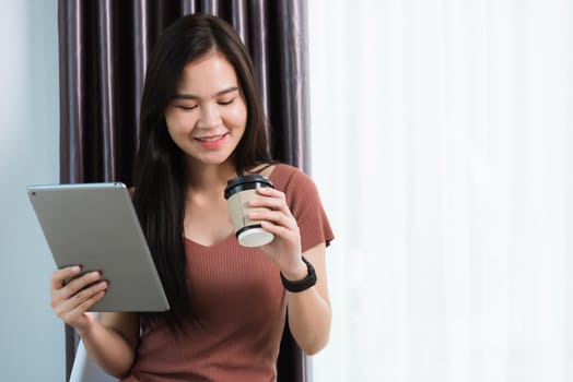 Work from home, Happy Asian young businesswoman smile video conference call or facetime by modern digital smart tablet computer she uses finger touching on screen, looking to tablet at home office