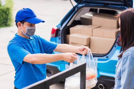 Asian young delivery man wear face mask he making grocery service giving rice food boxes plastic bags to woman customer receiving door at house after pandemic coronavirus, Back to new normal concept